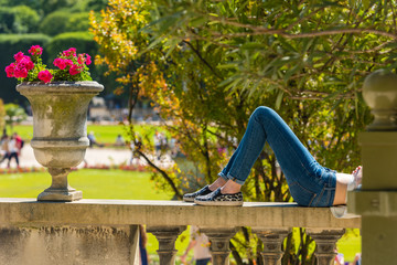 A young woman in jeans is lying and relaxing in a park