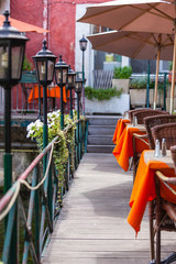 Small cafe with wicker furniture and umbrellas on a bridge