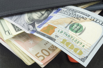 Euro and dollar bills in a black wallet