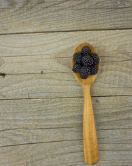 Blackberries in spoon on wooden background closeup shot