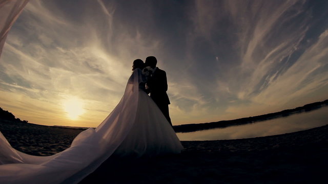 the groom kisses the bride at sunset on the beach silhouette