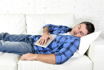 young attractive man sleeping at home couch relaxing after working with digital tablet pad