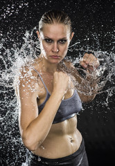 Fototapeta premium Athletic Woman in Combat Pose in Water Splashes