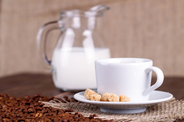 Coffee cup, cream, coffee grains and cane sugar
