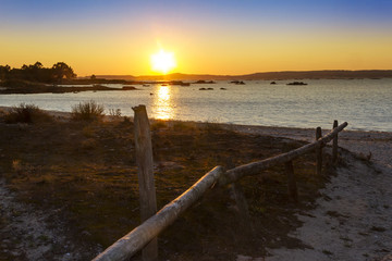 Fototapeta na wymiar Wooden fence on Espineiro beach at sunset