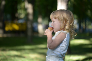 Cute little blonde girl is backlit against the background of