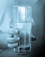 A girl holding a glass of water with the medicine.
