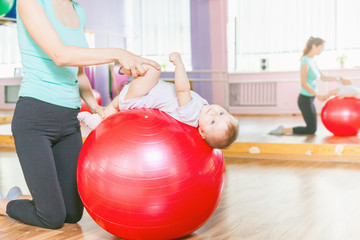 Naklejka premium Mother with happy baby doing exercises with gymnastic ball