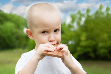 Little boy with pleasure eats is chocolate