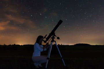 Woman looking through a telescope watching the stars.. Night sky, constellations, Draco, Ursa Major, Big Dipper, Botes.  - obrazy, fototapety, plakaty