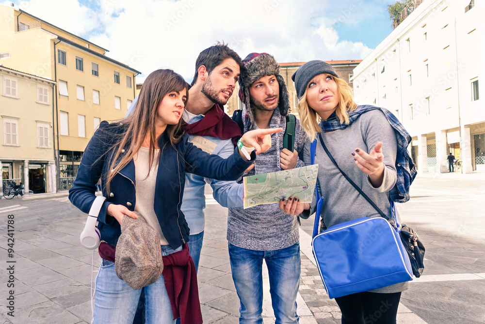 Wall mural group of tourists looking map - couples of best friends in holiday lost in old town center - young s