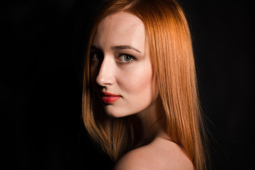 Fototapeta premium Dziewczyna z czerwonymi włosami średniej długości na ciemnym tle