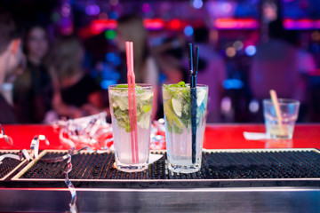 Two Mojito cocktails on a bar counter