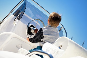 Little child sailor steering a sailboat as captain