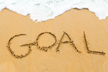 GOAL inscription written on sandy beach with wave approaching