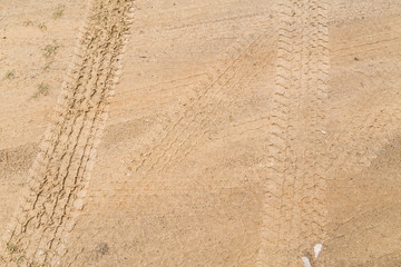 Fototapeta na wymiar Tire tracks on dry brown yellow dirt road