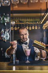 Barman is making cocktail at night club