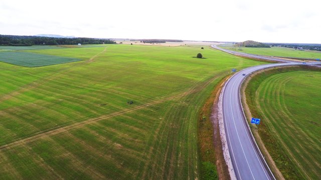 Cars on the high-speed road. Green fields. Sunset. Aerial footage