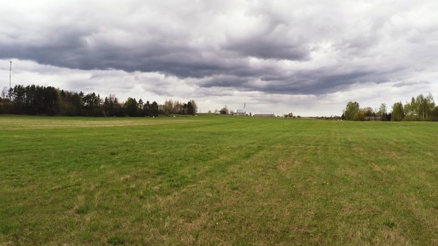Green field and massive clouds, aerial footage