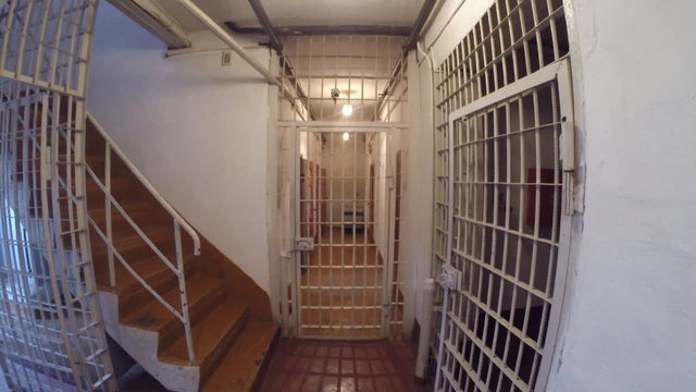 Moving inside the prison corridor with bars, locks and cameras 
