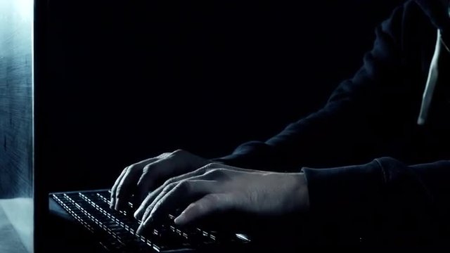 Man's hands typing on laptop computer keyboard, dark night. Shot in RAW 4K