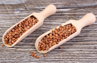 Buckwheat groats with spoon on wooden surface