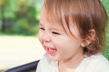 Happy toddler girl laughing while playing on a swing