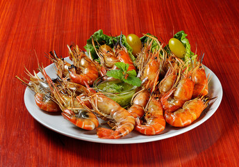 Delicious grilled shrimps with dipping sauce in the dish on red