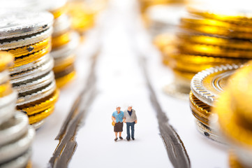 お金が積まれた道を歩く高齢者の夫婦