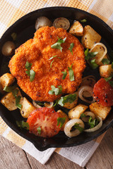 Weiner schnitzel, fried potatoes in a pan closeup. vertical top view
