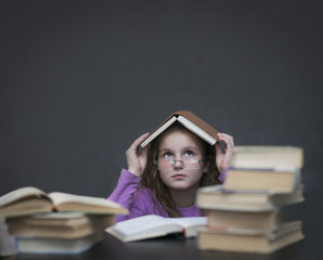 Школьница в очках прячется под книжкой домиком