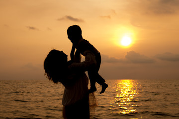 mother and son playing on the beach in dawn time