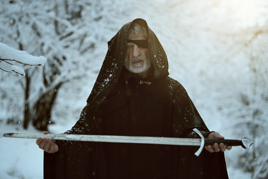 Old Black Hooded Man With Sword