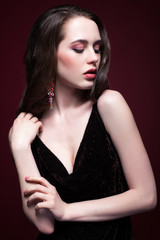 Naklejka premium Young beautiful woman in black dress on red marsala background