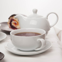 On the white tablecloth is a samovar, a teapot, a cup of tea and sweets, biscuits, rolls, tea,