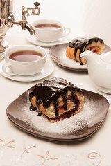 On the white tablecloth is a samovar, a teapot, a cup of tea and sweets, biscuits, rolls, tea,