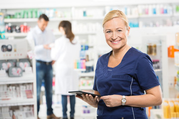Assistant Holding Digital Tablet At Pharmacy
