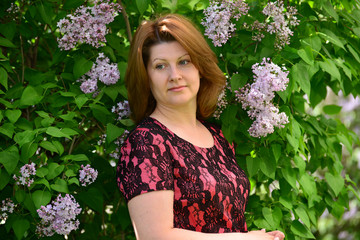 Middle-aged woman near blossoming lilac