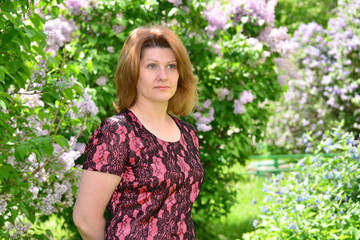 Middle-aged woman near blossoming lilac