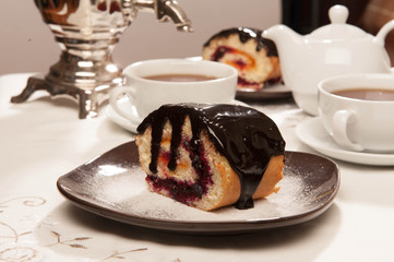 On the white tablecloth is a samovar, a teapot, a cup of tea and sweets, biscuits, rolls, tea,