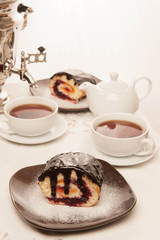 On the white tablecloth is a samovar, a teapot, a cup of tea and sweets, biscuits, rolls, tea,