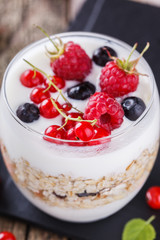 Breakfast with muesli, yogurt,honey and fresh berries in a glass on a wooden background. selective focus