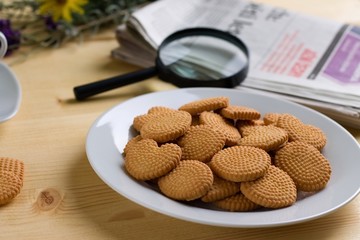 Biscuits on white plate and newspapers on wooden table