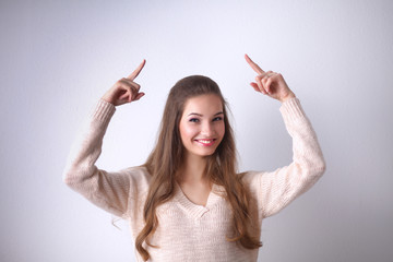Portrait of a smiling young woman pointing up, standing 