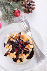 Fototapeta na wymiar Waffles with chocolate sauce and winter berries for christmas. Top view.