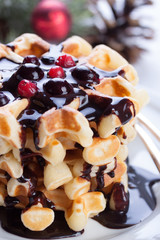 Waffles with chocolate sauce and winter berries for christmas. Closeup.