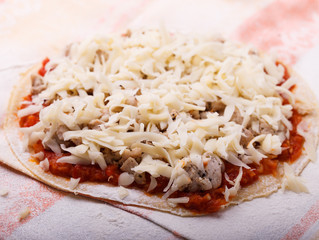 pizza preparation surrounded by ingredients