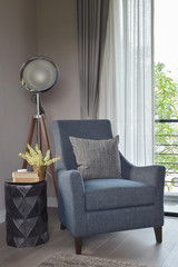 Light blue armchair with gray pillow and retro lamp in the livin