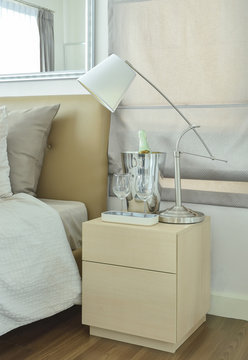 White table lamp with empty glasses and wine bottle on bed side