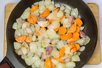 Stewed onions, carrots and garlic in a frying pan.